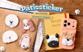 new product image set against wooden background introduces Patissticker Decoration Sticker and Magnet. Atop a cookie sheet from left to right, a white round dog, tan and white long eared dog, fluffy white dog, long faced tan and white dog, black and white short nosed dog on a notebook and tan and white short hair dog on the back of a peach cell phone case