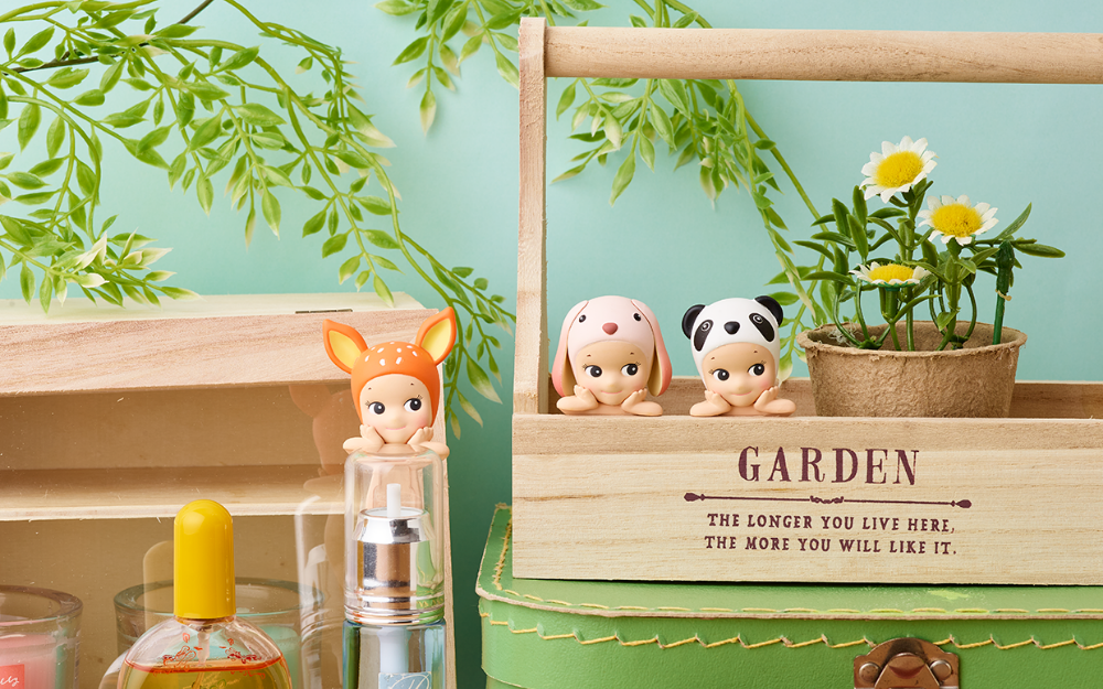 sonny angel hippers minifigures lifestyle image with fawn, lop ear, and panda mini figures attached to perfume bottles and a wooden basket. other props include fake plants and suitcase