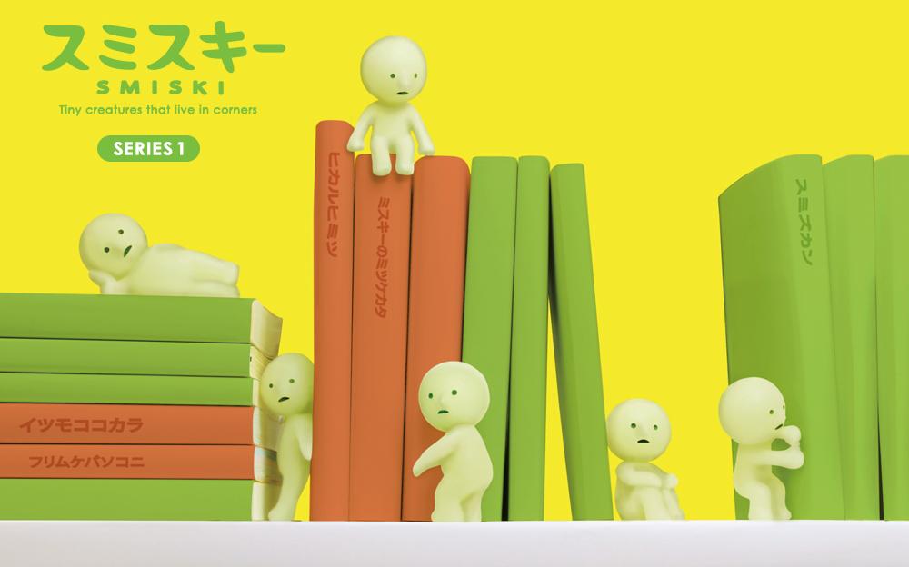 A collection of Smiski mini figures series 1 displayed on and around books, with a yellow background.