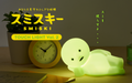 Smiski Touch Light, illuminated with a clock and plant on a wooden surface. Text reads "SMISKI Touch Light Vol. 2"