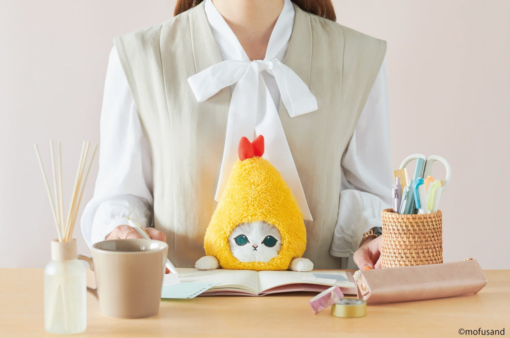 lifestyle image of posture pal mofusand shrimp meow. features a front facing view of person in a gray blouse writing in a planner using shrimp meow at desk