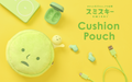 SMISKI in green text in both Japanese and English, above text "Cushion Pouch" set on yellow background. Light green charging brick, open green earpods case, green earpods, and green charging cable set around SMISKI Cushion Pouch with SMISKI figure tucked inside reaching outward.